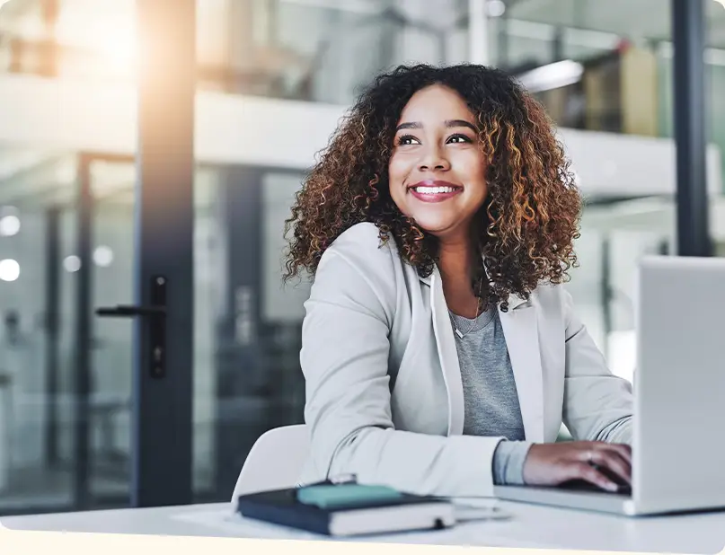 A business woman smiles while working on her laptop.