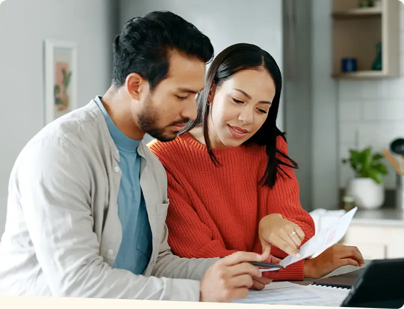 A man and woman inspecting a document together.  The man holds a pencil.